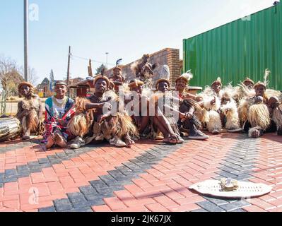 Johannesburg Südafrika - August 15 2007; Gruppe von Straßenkünstlern in traditioneller Tracht, die zusammen mit ihrem Sammelschild sitzen Stockfoto