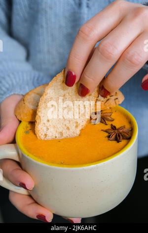 Frau mit hausgemachter Karotten-Ingwer-Curcuma-Suppe. Saisonale Kürbis traditionelle Suppe mit cremiger, seidiger Textur. Gesunde vegane, saubere Ernährung. Stockfoto