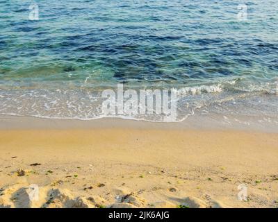 Meeresküste im Morgenlicht. Naturhintergrund von Sandstrand und transparentem, ruhigem Wasser im Sommer Stockfoto