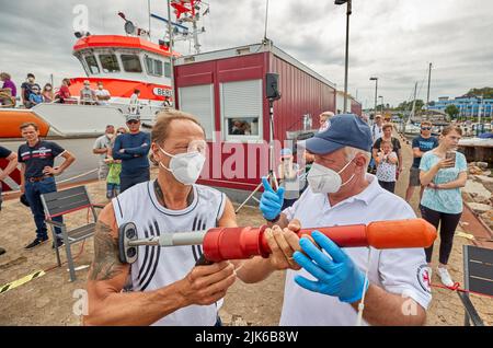 31. Juli 2022, Schleswig-Holstein, Laboe: Martin Bahr (l), Mitarbeiter und Besucher, lässt ihm am Sea Rescue Day 2022 im Hafen von Laboe das Linienschießgerät PLTR-75 von Uwe Radloff, Vorarbeiter des Seerettungskreuzers 'Berlin', erklären. Mit dem pneumatischen Leitungsschießgerät mit 90-m-Leitung wird eine Leitungsverbindung zu einem verletzten Schiff auf See hergestellt. Nach zwei Jahren organisierte der Deutsche Seerechtungsdienst (DGzRS) erneut den Tag der Seeretter 2022 an verschiedenen DGzRS-Stationen mit Präsentationen der Rettungstechnik, Mann-über-Bord-Übungen und Vorführungen der Rettungseinheit Stockfoto