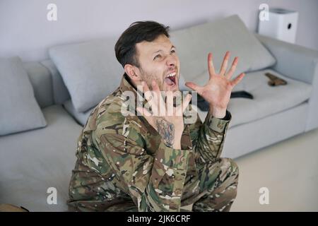 Militärveteran, der an PTSD leidet und auf dem Sofa schreit Stockfoto