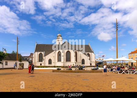 Entspannende Touristen mit Blick auf Andreaskerk (Andreaskirche), ein Gebäude aus dem 15.. Jahrhundert und ein Wahrzeichen in Katwijk, Südholland, Niederlande. Stockfoto