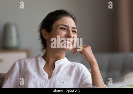 Glückliche schöne junge indische Frau, die zum Fenster schaut Stockfoto