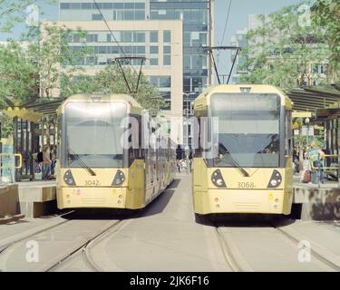 Manchester, Großbritannien - 2022. Juni: Zwei Metro-Straßenbahnen von Manchester an der Straßenbahnhaltestelle St. Peter's Square. Stockfoto