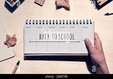 Zurück zur Schule Worte, Text auf Notizbuch. Schulbedarf aus Holz mit geringer Auswirkung. Studie Schreibwaren, Wochenplaner, Bleistifte, Notizbuch Stockfoto