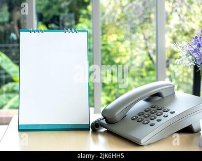 Weiß leer Desktop Flip-Top-Kalender Vorlage vertikalen Stil in der Nähe des Telefons auf Holzschreibtisch im Büro, für Corporate Design. Spiraltisch auf dem Schreibtisch Stockfoto