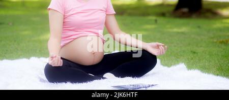 Glück junge asiatische Frau schwanger sitzen Yoga mit Meditation Lotus zur Entspannung im Park, Mutter Training für die Gesundheit in der üben Stockfoto