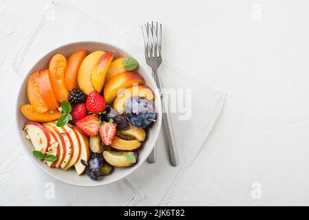 Schüssel mit gesunden frischen Obstsalat auf weißem Hintergrund Stockfoto