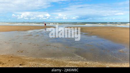 Menschen wandern am Strand entlang der Nordsee, Katwijk, Südholland, Niederlande. Stockfoto