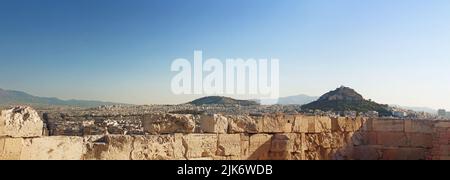 Blick auf die alte Akropolis-Mauer, die Stadt Athen und den Lycabettus-Berg (rechts) in Athen, Griechenland Stockfoto