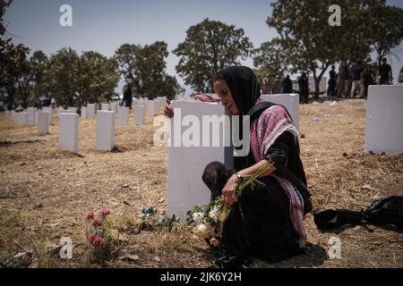 Barzan, Irak. 31.. Juli 2022. Eine ältere kurdische Frau trauert am Grab auf dem Anfal-Friedhof, nachdem die Überreste von 100 Barzani-Opfern begraben wurden, die Ende 1980s bei den Anfal-Operationen getötet wurden. Das Regime des baathistischen Irak unter Führung von Saddam Hussein hat Ende 1980s gewalttätige Operationen gegen die Kurden durchgeführt, bei denen mindestens 182.000 Tote und 90 % der kurdischen Dörfer zerstört wurden. Quelle: Ismael Adnan/dpa/Alamy Live News Stockfoto