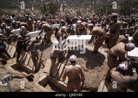 Barzan, Irak. 31.. Juli 2022. Kurdische Männer begraben die Überreste von 100 Barzani-Opfern, die Ende 1980s bei den Anfal-Operationen getötet wurden, auf dem Anfal-Friedhof in Barzan. Das Regime des baathistischen Irak unter Führung von Saddam Hussein hat Ende 1980s gewalttätige Operationen gegen die Kurden durchgeführt, bei denen mindestens 182.000 Tote und 90 % der kurdischen Dörfer zerstört wurden. Quelle: Ismael Adnan/dpa/Alamy Live News Stockfoto