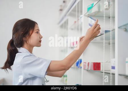 Medizin- und Gesundheitskonzept, Apothekerin prüft Medizin-Boxen in den Regalen in der Drogerie. Stockfoto