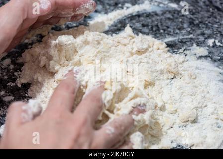 Frau mixt und knetet eine Mischung aus Mehl mit Kürbis, um einen Kuchen zuzubereiten Stockfoto