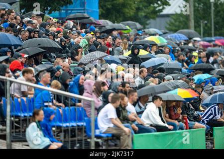 Lohne, Deutschland. 31.. Juli 2022. Fußball: DFB-Cup, TuS BW Lohne - FC Augsburg, 1.. Runde, Heinz-Dettmer-Stadion: Die Zuschauer sitzen bei strömendem Regen mit ihren Schirmen auf einer zusätzlichen Tribüne. Kredit: Christopher Neundorf/dpa - WICHTIGER HINWEIS: Gemäß den Anforderungen der DFL Deutsche Fußball Liga und des DFB Deutscher Fußball-Bund ist es untersagt, im Stadion und/oder vom Spiel aufgenommene Fotos in Form von Sequenzbildern und/oder videoähnlichen Fotoserien zu verwenden oder zu verwenden./dpa/Alamy Live News Stockfoto