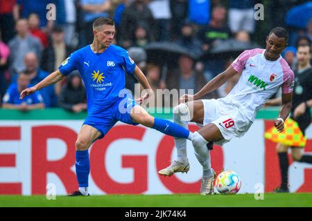 Lohne, Deutschland. 31.. Juli 2022. Fußball: DFB-Cup, TuS BW Lohne - FC Augsburg, 1. Runden, Heinz-Dettmer-Stadion: Lohne's Lennard Prüne (l.) und Augsburgs Felix Uduokhai kämpfen um den Ball. Kredit: Christopher Neundorf/dpa - WICHTIGER HINWEIS: Gemäß den Anforderungen der DFL Deutsche Fußball Liga und des DFB Deutscher Fußball-Bund ist es untersagt, im Stadion und/oder vom Spiel aufgenommene Fotos in Form von Sequenzbildern und/oder videoähnlichen Fotoserien zu verwenden oder zu verwenden./dpa/Alamy Live News Stockfoto