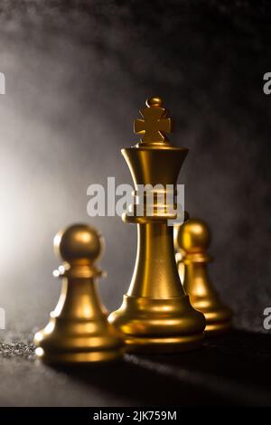 goldene Schachfiguren in Nahaufnahme auf grauem Hintergrund Stockfoto