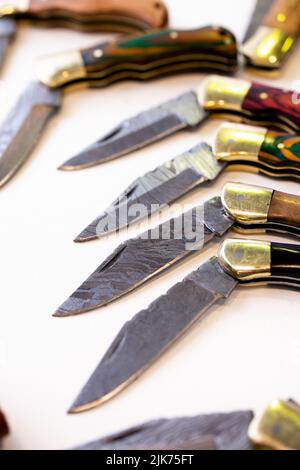 Verschiedene Messer und Lederetuis auf weißem Hintergrund Stockfoto