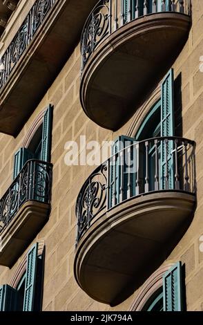 In Barcelona, Katalonien, Spanien, Europa trifft der Sonnenschein auf schmiedeeiserne Balkone aus Stein und Schmiedeeisen. Stockfoto