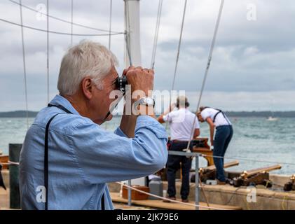 Zuschauer bei der jährlichen cowes Week Regatta, die durch ein Fernglas das Jachtrennen anschaut und die Raxces auf der Insel wight bei der cowes Week beobachtet. Stockfoto