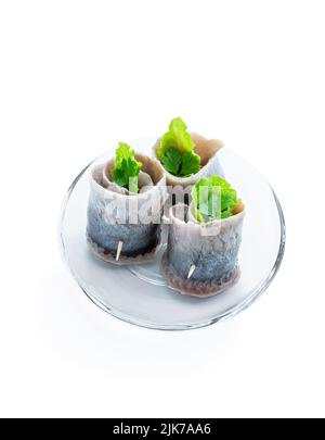 Appetitlich eingelegte Heringsrollen gefüllt mit Frischkäse und Salatblättern isoliert auf Weiß Stockfoto