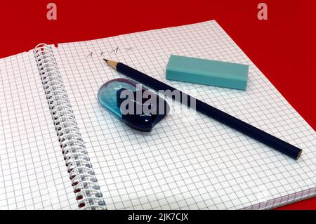 Schreibutensilien: Bleistift, Spitzer und Radierer auf einem karierten Pad Stockfoto