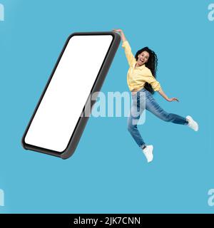 Frau Springt Berühren Große Handy Leeren Bildschirm Über Blauen Hintergrund Stockfoto