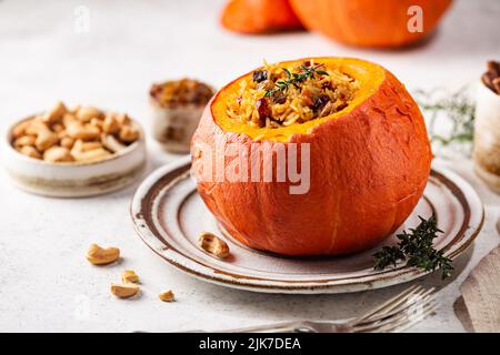 Tasty baked pumpkin stuffed with rice, vegetables, cashews and dried fruits on white background Stock Photo