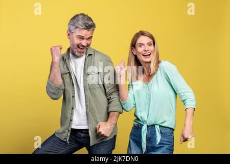 Portarit von fröhlichen, kaukasischen Ehegatten mittleren Alters, die tanzen und dummen und gemeinsam Lieblingsmusik genießen Stockfoto