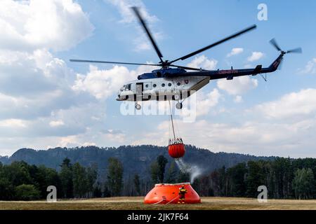 Mezni Louka, Tschechische Republik. 31.. Juli 2022. Der slowakische Hubschrauber bringt Wasser aus einem speziellen 54,5-Kubikmeter-Beutel, der sich in der Nähe des Feuers befindet und von Tankern in der Nähe von Mezni Louka, Hrensko, im Nationalpark Ceske Svycarsko (Tschechische Schweiz), Tschechische Republik, gefüllt wird, in den Eimer, 31. Juli 2022. Das Feuer im Nationalpark Tschechische Schweiz dauert seit acht Tagen an. Quelle: Ondrej Hajek/CTK Photo/Alamy Live News Stockfoto