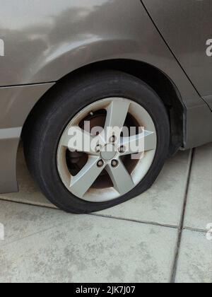 Reifenpanne auf einem Auto, das in der Auffahrt geparkt ist. Stockfoto