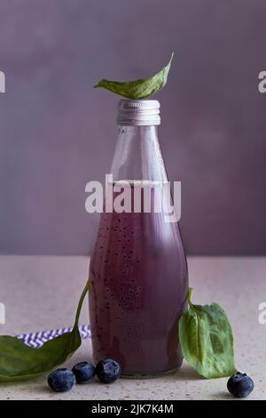 Alkoholfreie, gesunde Bio-Flasche mit Heidelbeeren, Samen, Basilikumextrakt, Blättern. Weiches, erfrischendes asiatisches Getränk. Stockfoto