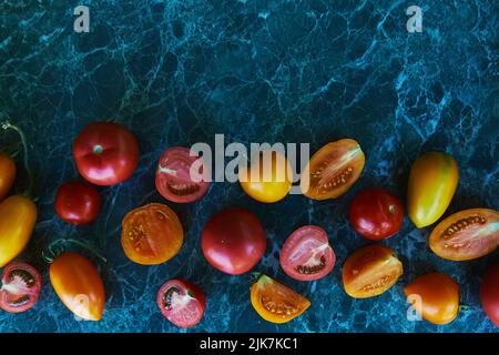 Rote, orange und gelbe Tomaten auf grünem Marmorboden. Natürliches, biologisches Gemüse. Speicherplatz kopieren. Essen von oben. Stockfoto