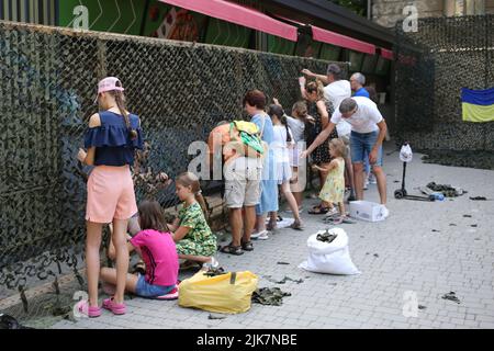 Odessa, Ukraine. 31.. Juli 2022. Erwachsene und Kinder werden während der Veranstaltung gesehen, wie sie ein Tarnnetz für das Militär weben. "Mein Land Ukraine" eine Wohltätigkeitsveranstaltung fand während eines Urlaubs im Sommertheater des Stadtgartens statt. Das Ziel war es, Mittel für die Bedürfnisse der Streitkräfte der Ukraine zu sammeln. Kredit: SOPA Images Limited/Alamy Live Nachrichten Stockfoto