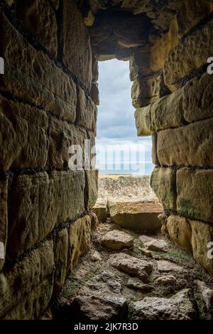 Blick durch den alten Steinbogen zur Küste und zum Meer dahinter Stockfoto