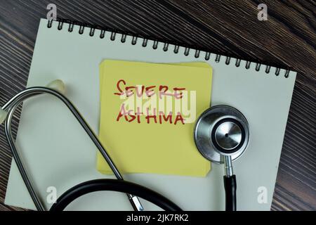 Konzept der schweren Asthma Schreiben Sie auf Haftnotizen mit Stethoskop isoliert auf Holztisch. Stockfoto