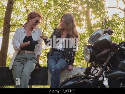 Zwei Freundinnen treffen sich und spielen die Steinpapierschere am Rande einer Waldstraße Stockfoto