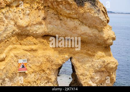 Lagos, Portugal. 21.. Juli 2022. Am Strand 'Praia do Camilo' warnt ein Schild auf einem Felsen vor fallenden Felsen. Quelle: Viola Lopes/dpa/Alamy Live News Stockfoto