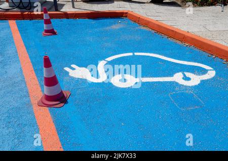 Albufeira, Portugal. 23.. Juli 2022. Führungskegel stehen auf zwei Parkplätzen als Barriere und Ladesäulen mit auf sie lackierten Piktogrammen für Elektroautos. Quelle: Viola Lopes/dpa/Alamy Live News Stockfoto