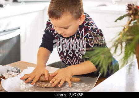 Ein Junge bereitet in der Küche Lebkuchen zu. Weihnachtstraditionen der Familie. Freizeit des Kindes während der Neujahrsferien. Stockfoto