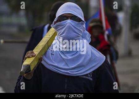 San Salvador, El Salvador. 31.. Juli 2022. Ein maskierter Student, der eine Stange hält, schaut während einer Demonstration zum Gedenken an den 47.. Jahrestag des Massakers an Universitätsstudenten durch das Militär am 30. Juli 1975 und den anhaltenden Ausnahmezustand, der vom salvadorianischen Kongress angeordnet wurde, zu. (Foto von Camilo Freedman/SOPA Images/Sipa USA) Quelle: SIPA USA/Alamy Live News Stockfoto