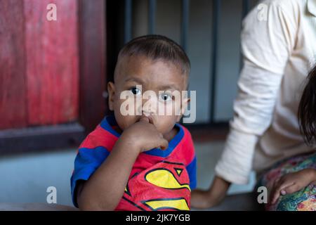 Ein junger Thai-Junge saugt sich den Finger und starrt auf die Kamera Stockfoto