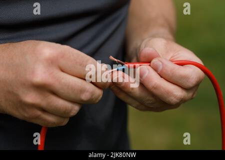 Abgetrenntes Netzkabel, das in den Händen und Fingern eines mannes gehalten wird und bereit ist, miteinander verbunden zu werden Stockfoto