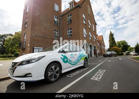 Ein Elektroauto mit Werbegrafiken, das von einem Ratsmitglied aus dem Bezirk Spelthorne vor den ratsbüros in Staines verwendet wird Stockfoto