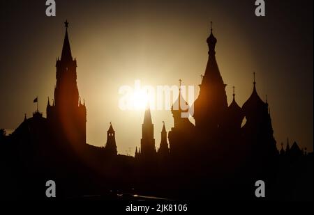 Moskauer Kreml und Basilius-Kathedrale bei Sonnenuntergang, Russland. Szenerie des Stadtzentrums von Moskau und Sonne am Sommerabend. Silhouetten von Moskauer Wahrzeichen in Stockfoto