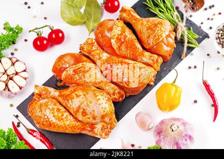 Hintergrund für ein Banner mit Fleisch mit Gewürzen.Kochen Hähnchendrumsticks.Rohe Hähnchenbeine in einer Marinade mit Rosmarin auf einem Hintergrund.mariniertes Huhn Stockfoto