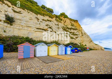 Eine Reihe von Strandhütten am Fuße der Kreidefelsen bei Beer, einem kleinen Küstendorf an der Lyme Bay an der Jurassic Coast of East Dorset, Südwestengland Stockfoto