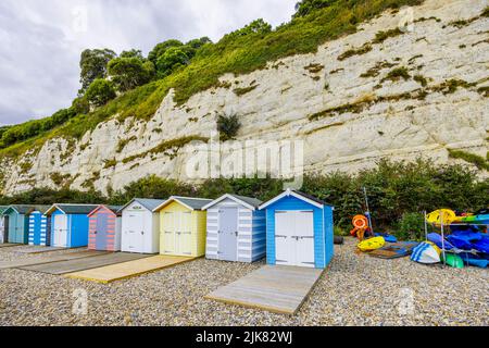 Eine Reihe von Strandhütten am Fuße der Kreidefelsen bei Beer, einem kleinen Küstendorf an der Lyme Bay an der Jurassic Coast of East Dorset, Südwestengland Stockfoto