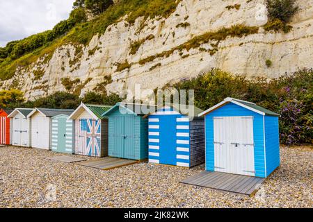 Eine Reihe von Strandhütten am Fuße der Kreidefelsen bei Beer, einem kleinen Küstendorf an der Lyme Bay an der Jurassic Coast of East Dorset, Südwestengland Stockfoto