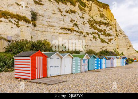 Eine Reihe von Strandhütten am Fuße der Kreidefelsen bei Beer, einem kleinen Küstendorf an der Lyme Bay an der Jurassic Coast of East Dorset, Südwestengland Stockfoto